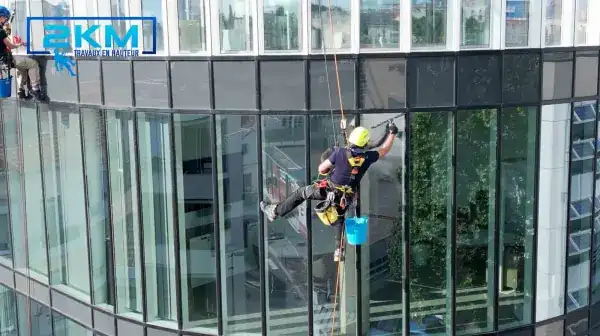 Cordiste 2KM nettoyant les vitres d'une facade vitree courbe en hauteur